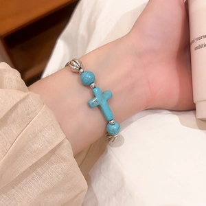 Detail of beaded turquoise bracelet featuring vintage silver spacer beads and cross pendant
