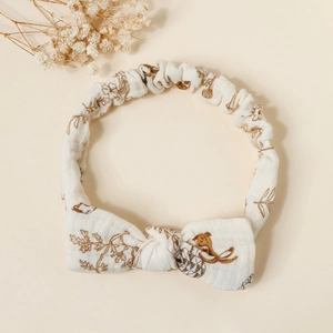 Detailed view of cream baby headband featuring a bow design and nature patterns