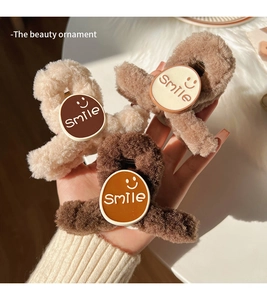 Close-up of plush smile face hair claws in cream and brown fluffy faux fur texture