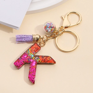 Detail of resin letter K keychain with mixed colorful sequins and a purple tassel