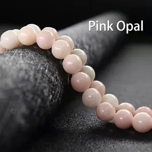 Macro shot of 8-10mm pink opal round beads with a smooth greasy luster on a black stand