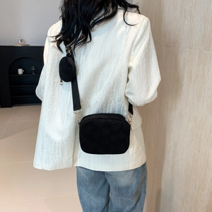 Detailed view of black crossbody bag with embossed heart patterns and mini pouch