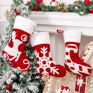 Three embroidered Christmas stockings with reindeer and snowflake hanging by a fireplace