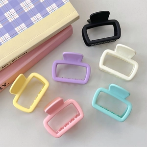 Detailed view of six matte rectangular hair claws in various colors on a flat surface