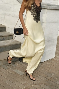 Detailed close-up of champagne satin fabric with black lace trim on a long dress