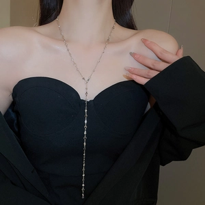 Model wearing a silver Y-shaped tassel necklace with heart elements on a black outfit