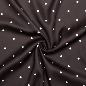 Macro d'un tissu marron foncé à pois blancs montrant le drapé doux et la texture