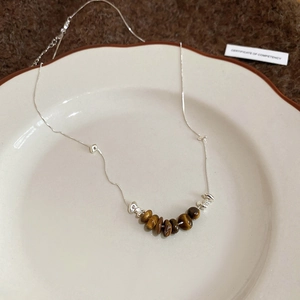 Detail of tiger eye stone beads and irregular silver metal accents on a necklace