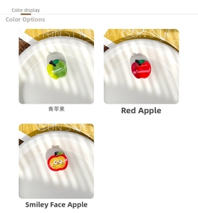 Detail view of glossy apple-shaped hair claws in green, red, and smiley patterns