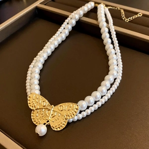 Double-layer pearl necklace with a detailed golden butterfly pendant on a brown tray