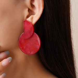 Close-up of oversized red marble acrylic earrings worn on model for style and size reference