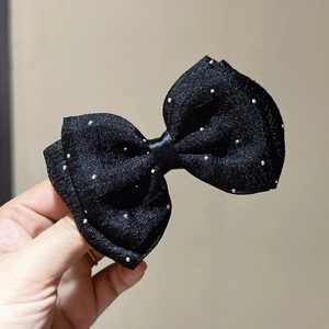 Detailed close-up of a handmade black mesh hair bow with sparkling silver glitter dots