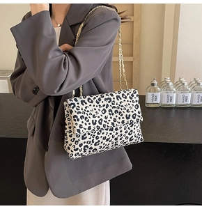 Close-up of leopard print shoulder bag with gold chain strap worn with a grey blazer