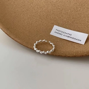 Minimalist S925 sterling silver beaded open ring on a dark cork tray edge