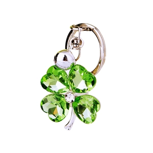 Green crystal four-leaf clover keychain with silver bell and polished metal ring