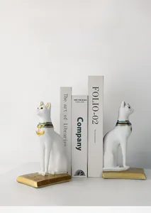 Detail of white Egyptian cat bookends with golden hieroglyphic base for office decor