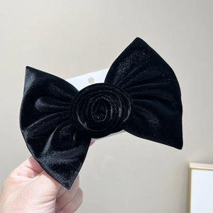 Détail d'une grande pince à cheveux en velours noir avec un design chic de rose centrale