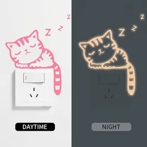 Luminous sleeping cat wall sticker for light switches showing day and night glowing effect