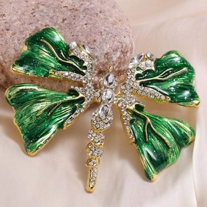 Macro detail of a golden dragonfly brooch with green enamel and sparkling crystals