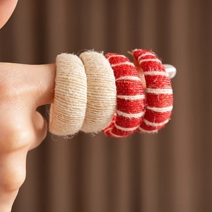 Close-up of knit fabric hair rings in cream and red striped patterns on fingers