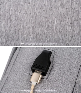 Detail view of grey fabric texture and external USB charging port on the laptop backpack