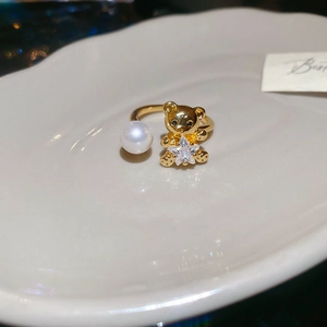 Detail of gold open ring featuring a cute bear holding a star and a white pearl