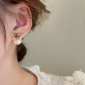Detail of golden bee earrings with shimmering rhinestones and a hanging white pearl