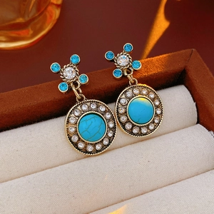 Macro detail of vintage gold earrings with turquoise stones and rhinestones in a velvet box