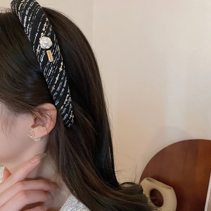 Detail of black tweed headband with white camellia flower and gold metallic logo