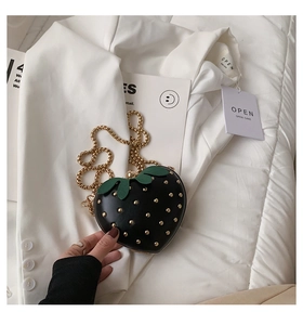 Detail of strawberry-shaped black bag with golden studs and metal chain strap