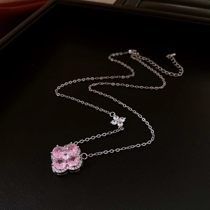 Détail d'un collier trèfle à quatre feuilles avec zircons roses sur fond de cuir noir