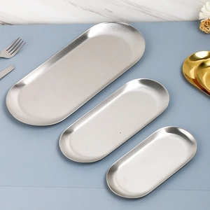 Three sizes of oval stainless steel storage trays in silver finish on blue desktop