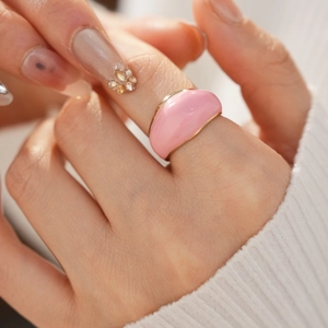 Close-up of pink enamel dome ring with gold edges on white knit sweater background