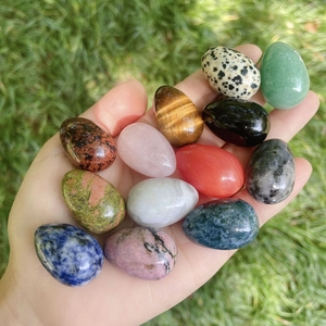 Polished 30mm natural gemstone egg collection in hand including rose quartz and tiger eye