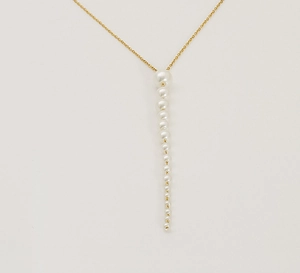 Vue détaillée d'un collier en chaîne dorée avec un élégant tombé de perles blanches