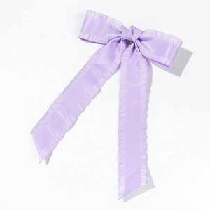 Detail of lavender satin bow hair clip featuring pleated edges and long ribbons