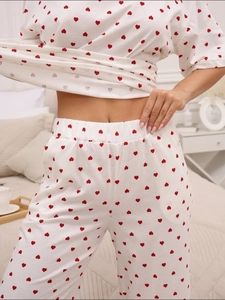 Detailed close-up of white pajama set with red heart print and elastic waistband design