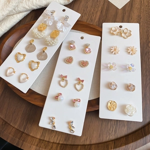 Close-up of pearl and rhinestone bow earring set displayed on elegant wooden tray