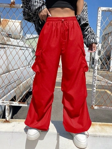 Detail view of bold red cargo pants featuring an elastic drawstring waist and side pockets