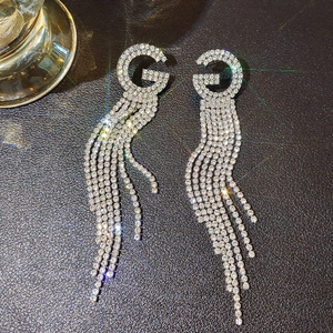 Macro shot of silver tassel earrings with G-shape top and sparkling white crystal chains