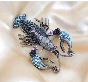 Macro detail of lobster brooch featuring deep blue rhinestones on champagne silk fabric