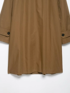 Detail of khaki trench coat featuring adjustable sleeve cuffs and rear back slit design