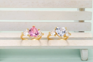 Verstellbare goldene Ringe mit rosa und klaren herzförmigen Kristallen auf einer Holzbank