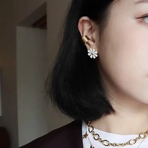 Chic white flower stud earring and layered gold ear cuff worn by a female model