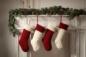 Close-up of four red and white knitted Christmas stockings hanging on a festive fireplace
