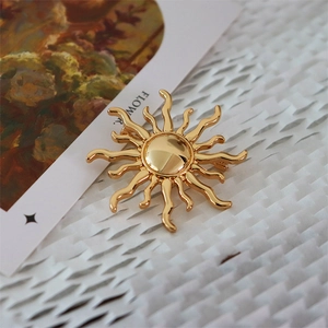 Detailed macro view of a vintage golden sunburst brooch with mirror polished finish