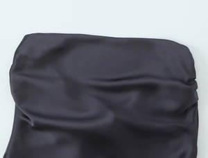 Détail macro du tissu en satin brillant montrant une texture lisse et des drapés