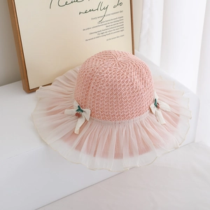 Detailed macro view of girls pink straw hat with lace rim and cherry bow ornaments