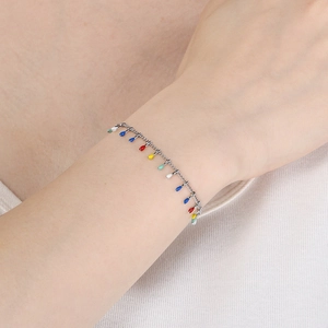 Close-up of a silver titanium steel bracelet with colorful drop pendants on a wrist