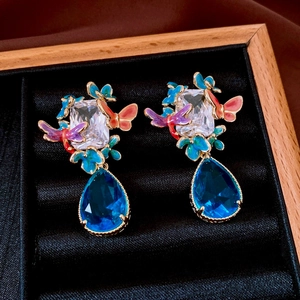 Macro view of gold plated butterfly earrings with blue gemstone in a velvet gift box